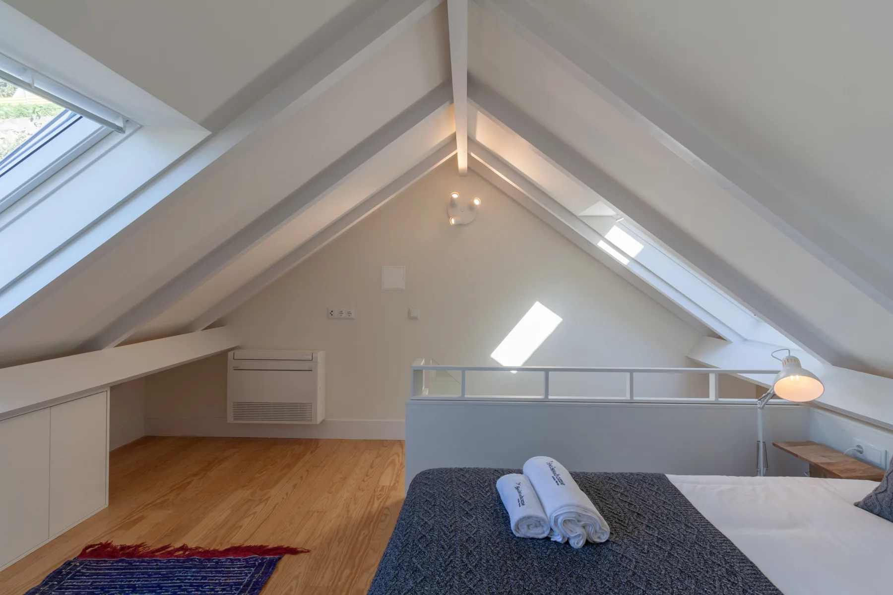 A bright attic bedroom with a sloped ceiling and a bed.