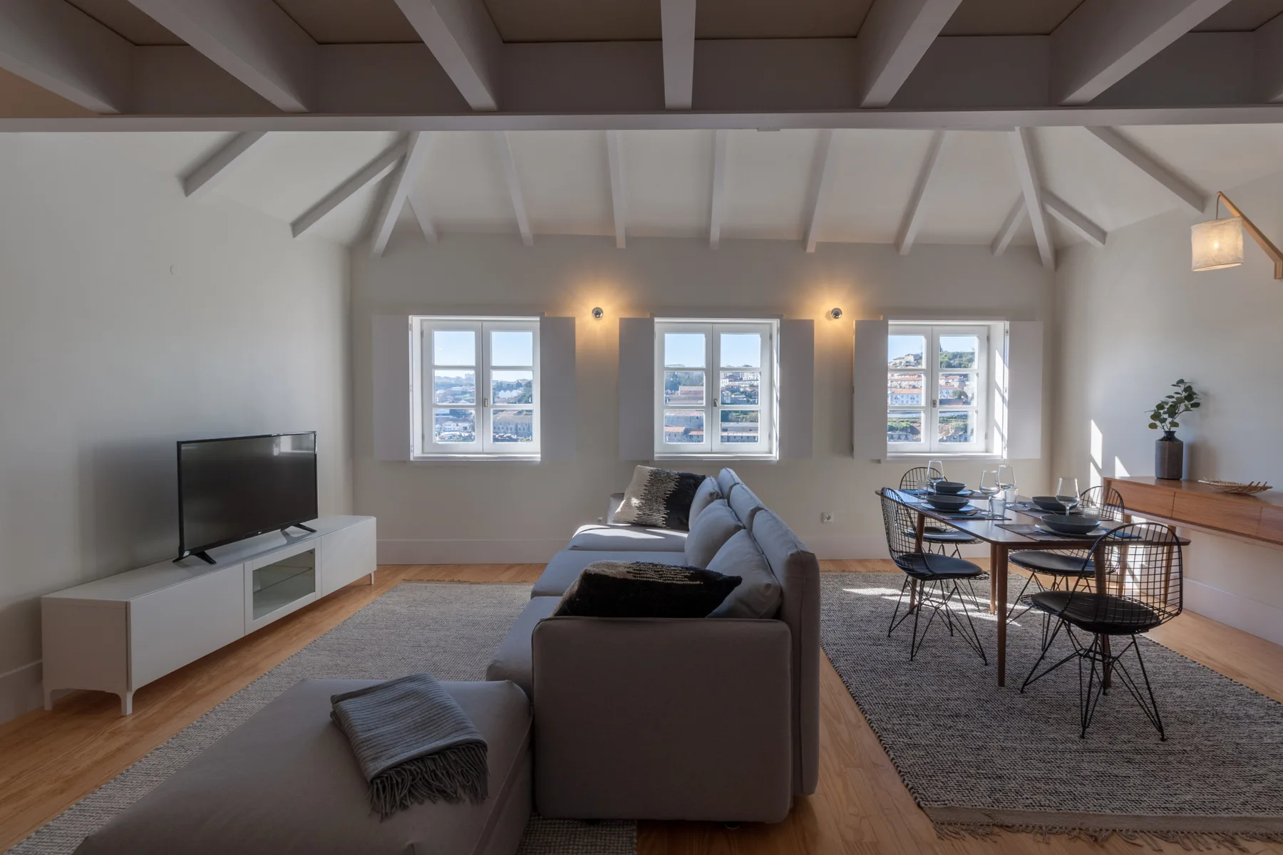 A living and dining area with seating, a television, and windows.