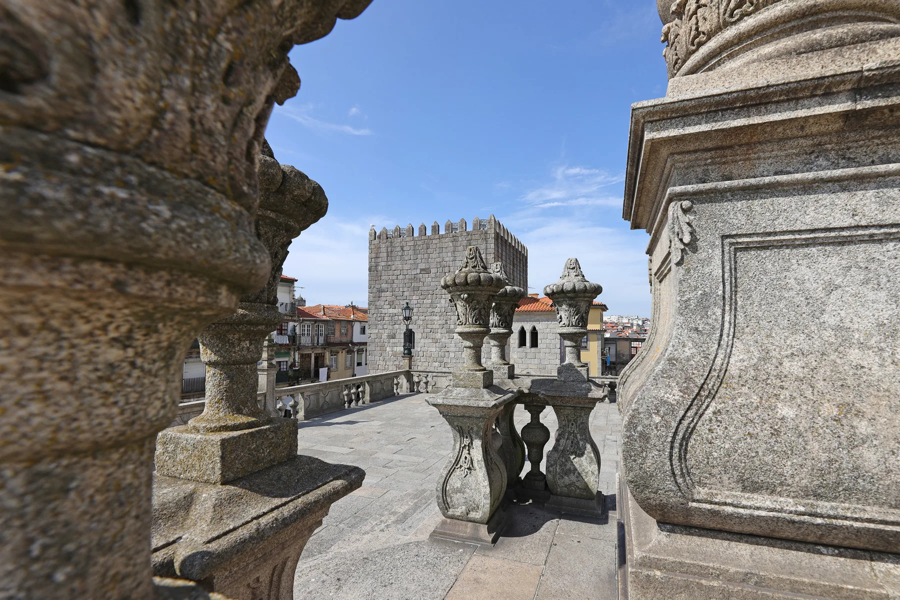 A stone terrace overlooks historic buildings beneath a clear blue sky.