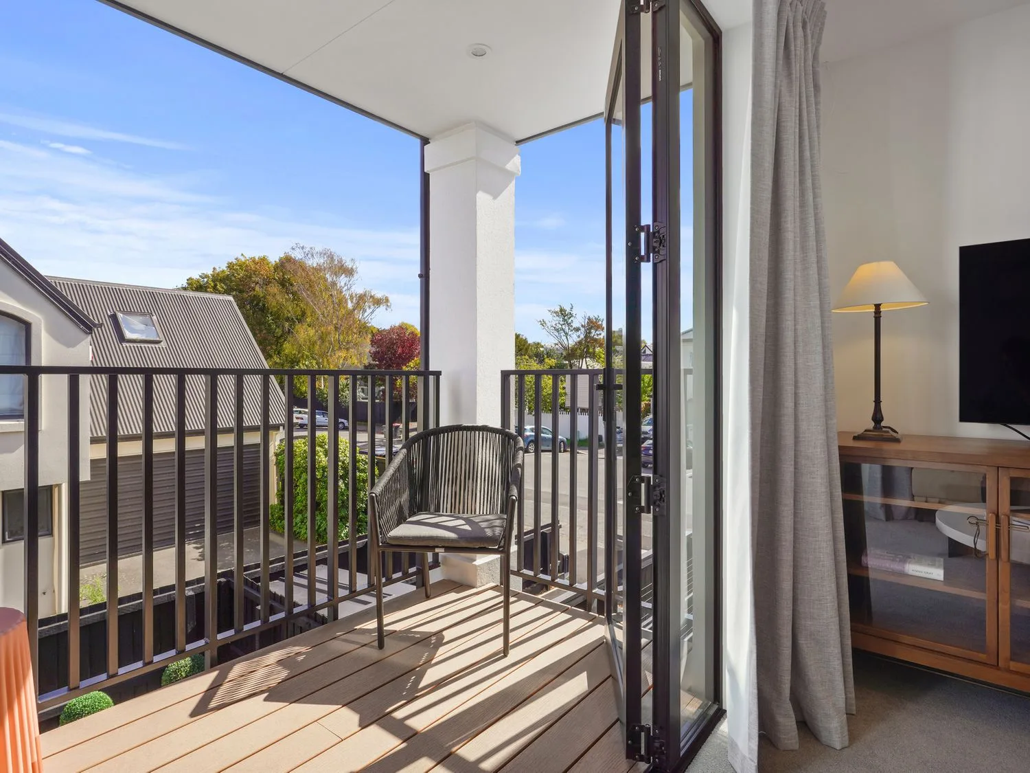 Un balcón con una silla y una barandilla con vistas a una zona de estacionamiento y a edificios vecinos en Modern Central Apartment - Christchurch Apartment, en Monavale