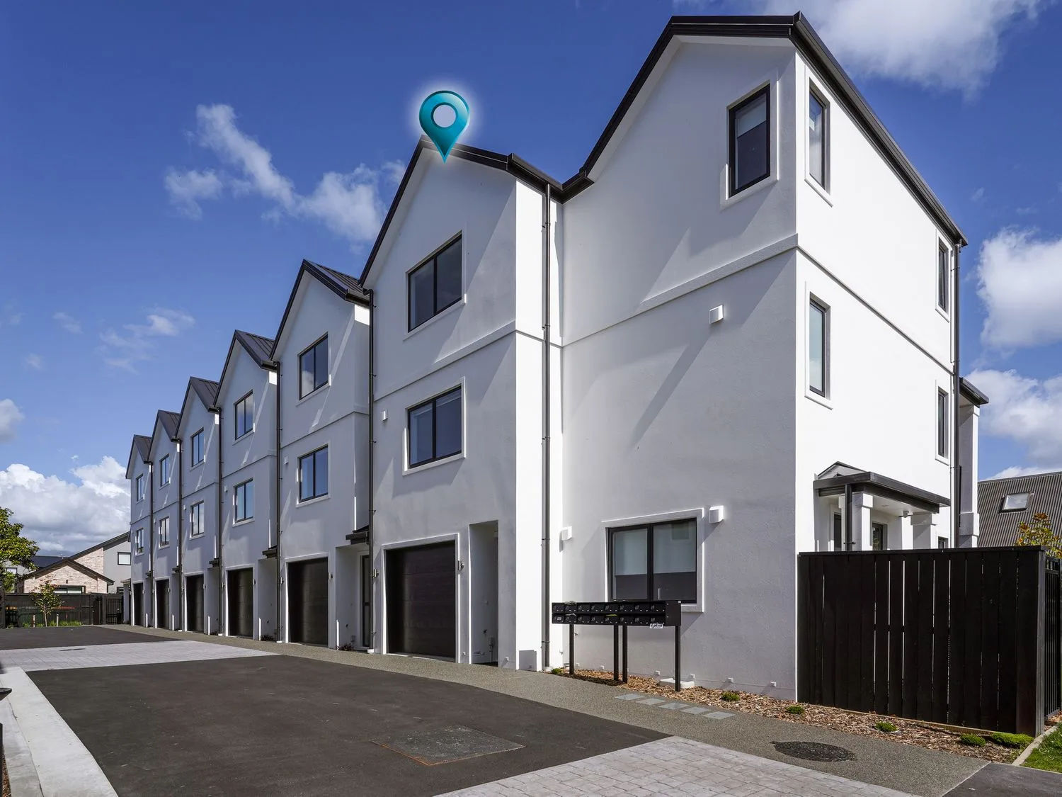 Una hilera de casas adosadas modernas de color blanco con garajes y buzones en Modern Central Apartment - Christchurch Apartment, en Monavale