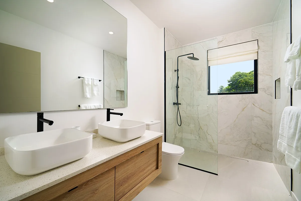A bright bathroom with a double vanity and a glass shower.