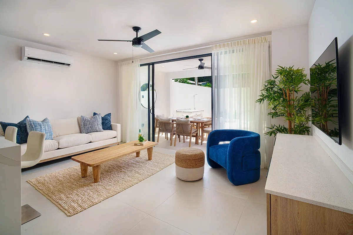 A bright living room with a sofa and blue armchair beside glass doors.