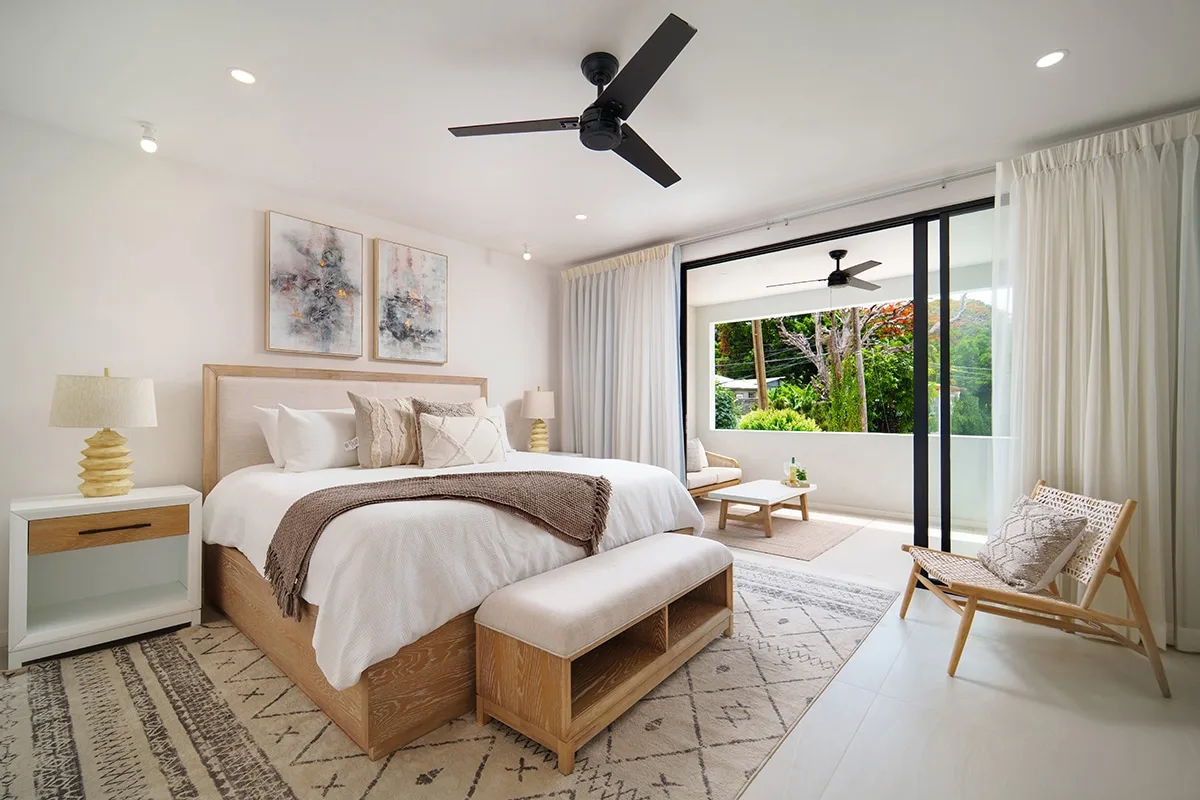 A bright bedroom with a bed, bedside table, and sliding glass doors.