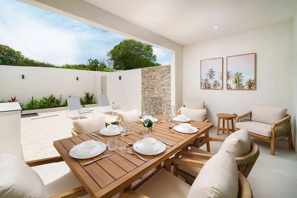 An outdoor dining area with a wooden table and cushioned seating.