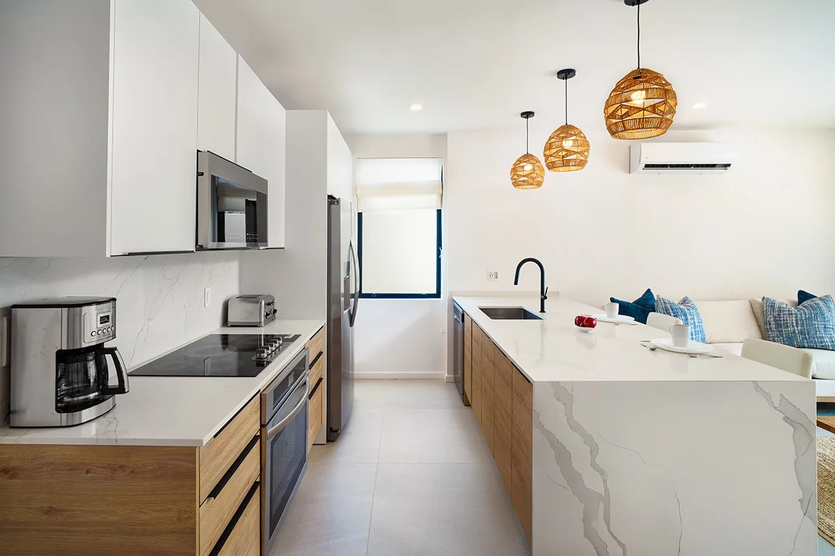 A modern kitchen with a large island and pendant lights.