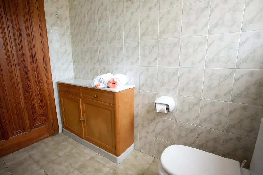 Un baño con azulejos, un mueble de madera y un inodoro.