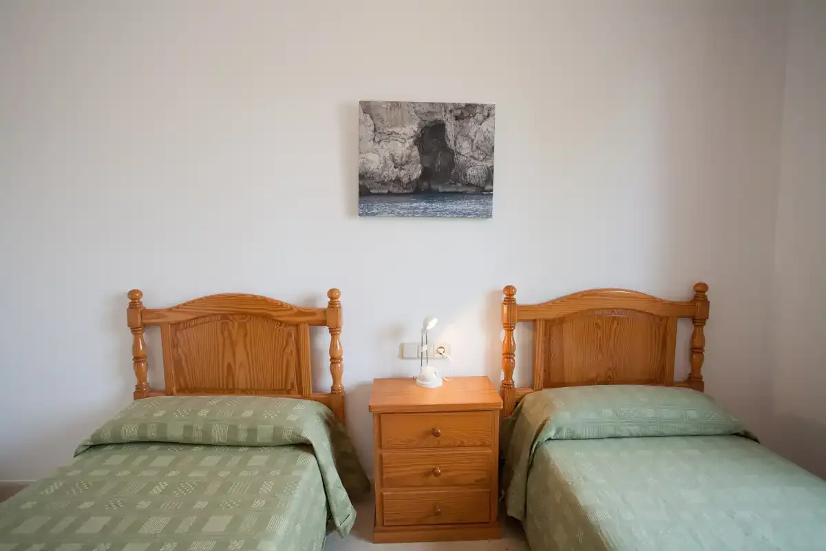 Un dormitorio con dos camas y una mesita de madera entre ellas.