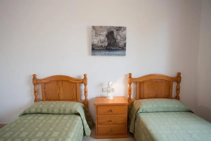 Un dormitorio con dos camas individuales y una mesita de noche de madera.