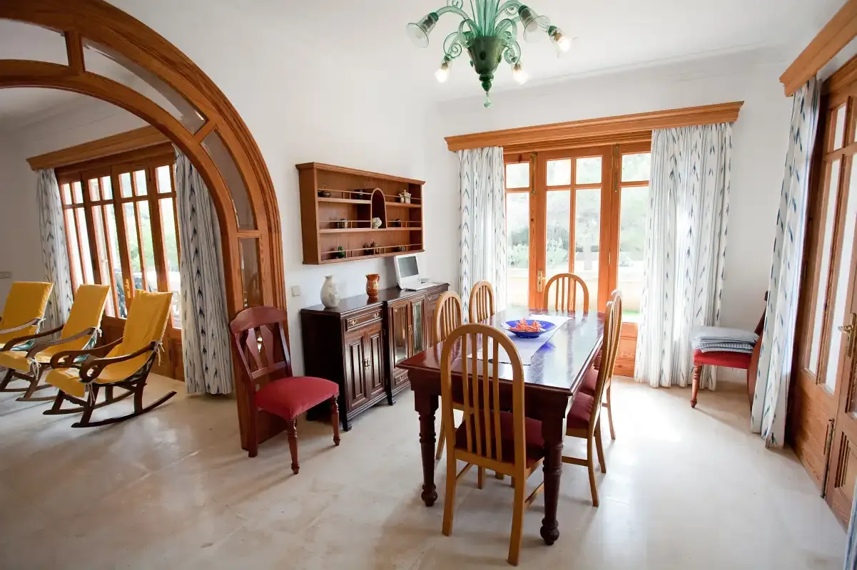Un comedor luminoso con una mesa de madera y sillas junto a una zona de estar.