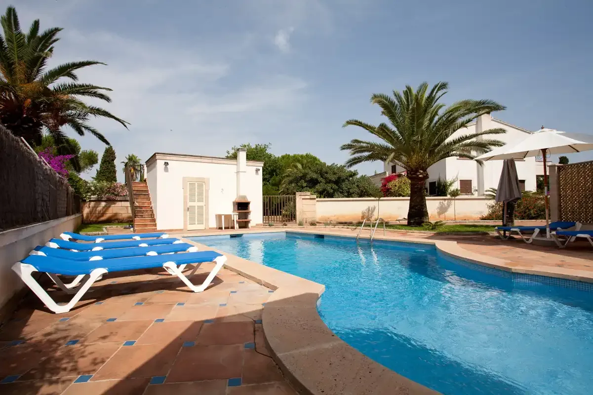 Una piscina al aire libre con asientos para tomar el sol y palmeras.