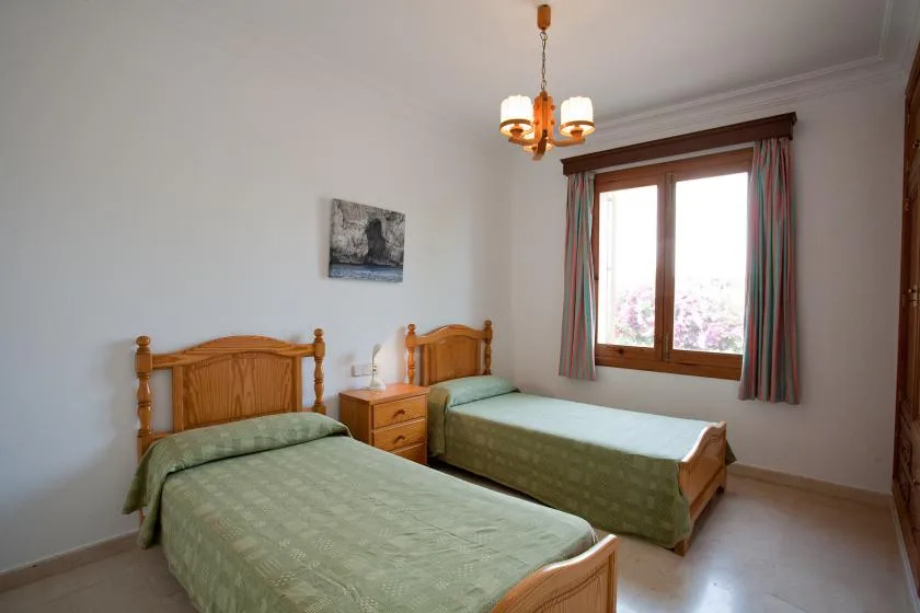 Un dormitorio con dos camas, ropa de cama verde y una ventana.