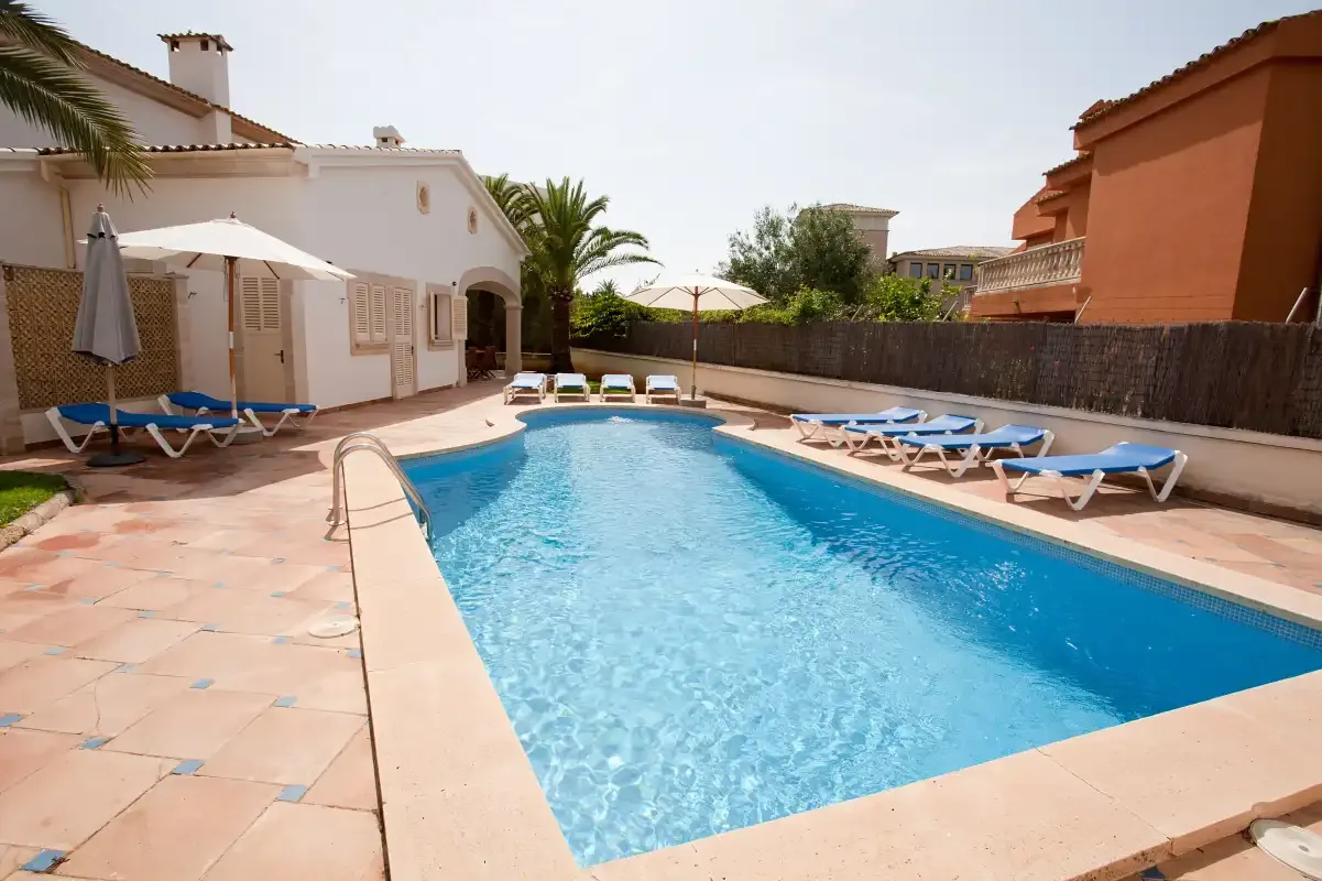 Una piscina está en un patio pavimentado junto a edificios residenciales.