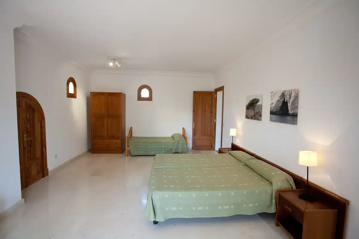 Un dormitorio con una cama grande, una cama pequeña y puertas de madera.