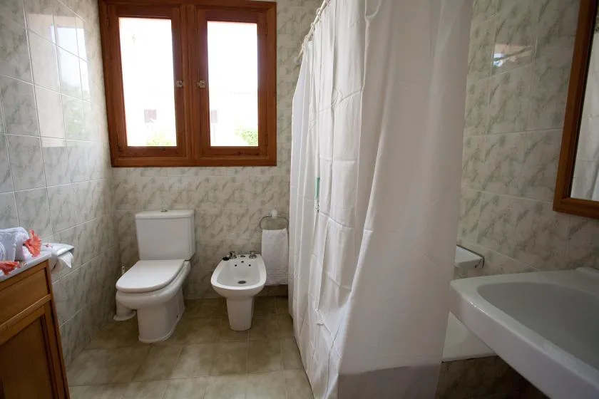 Un baño de azulejos con inodoro, bidé, bañera y cortina de ducha.