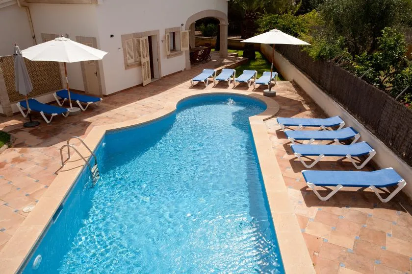 Una piscina rodeada de un patio de baldosas con tumbonas.
