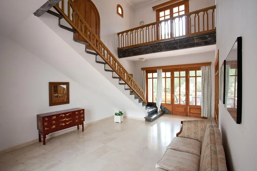 Una sala luminosa con una escalera de madera y una zona para sentarse.