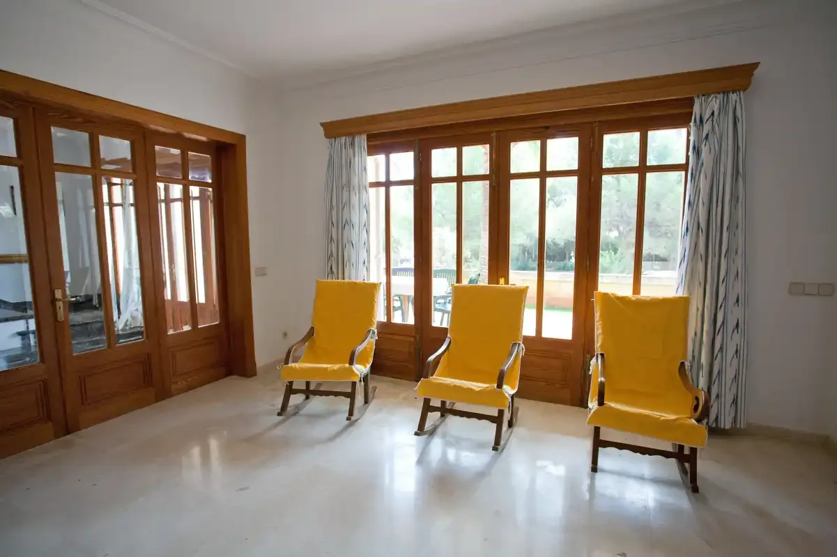 Una sala de estar luminosa con asientos amarillos junto a grandes ventanas.