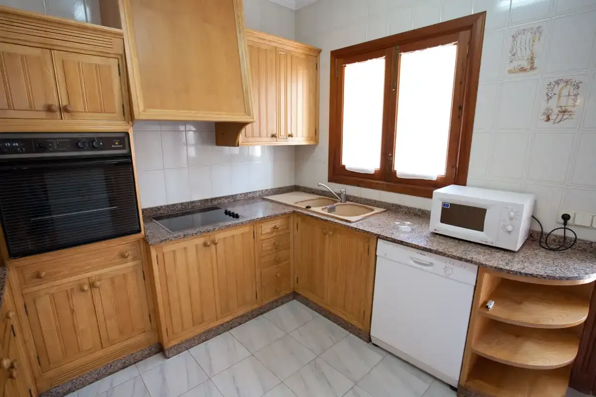 Una cocina con armarios de madera, una encimera y una ventana.
