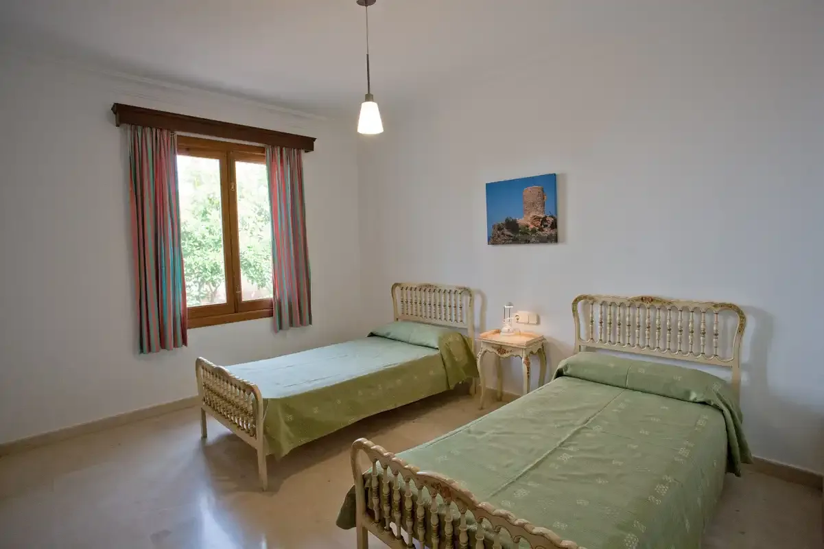 Un dormitorio con dos camas, una mesita de noche y una ventana con cortinas.