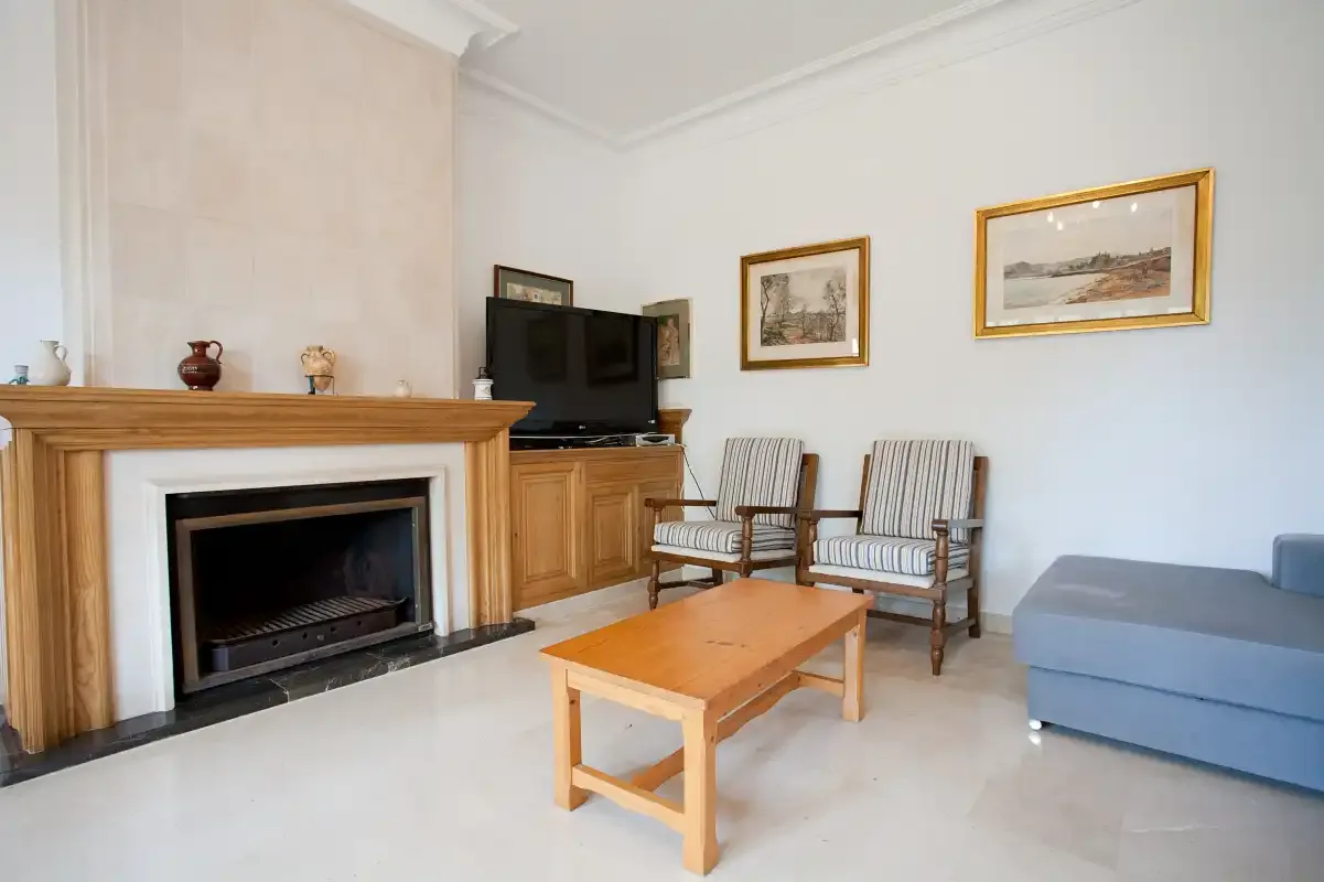 Una sala de estar con chimenea, asientos y una mesa de centro de madera.