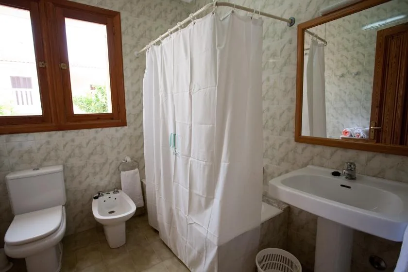 Un baño con cortina de ducha, inodoro, bidé y lavabo.