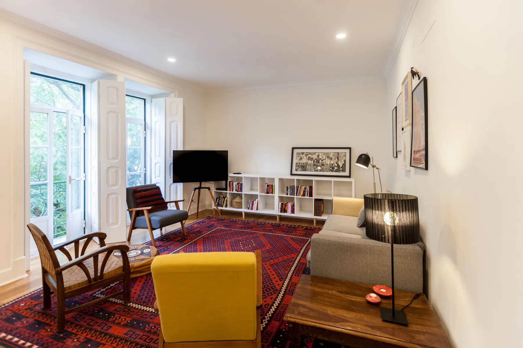 Una sala de estar luminosa con asientos alrededor de una alfombra estampada y un televisor.
