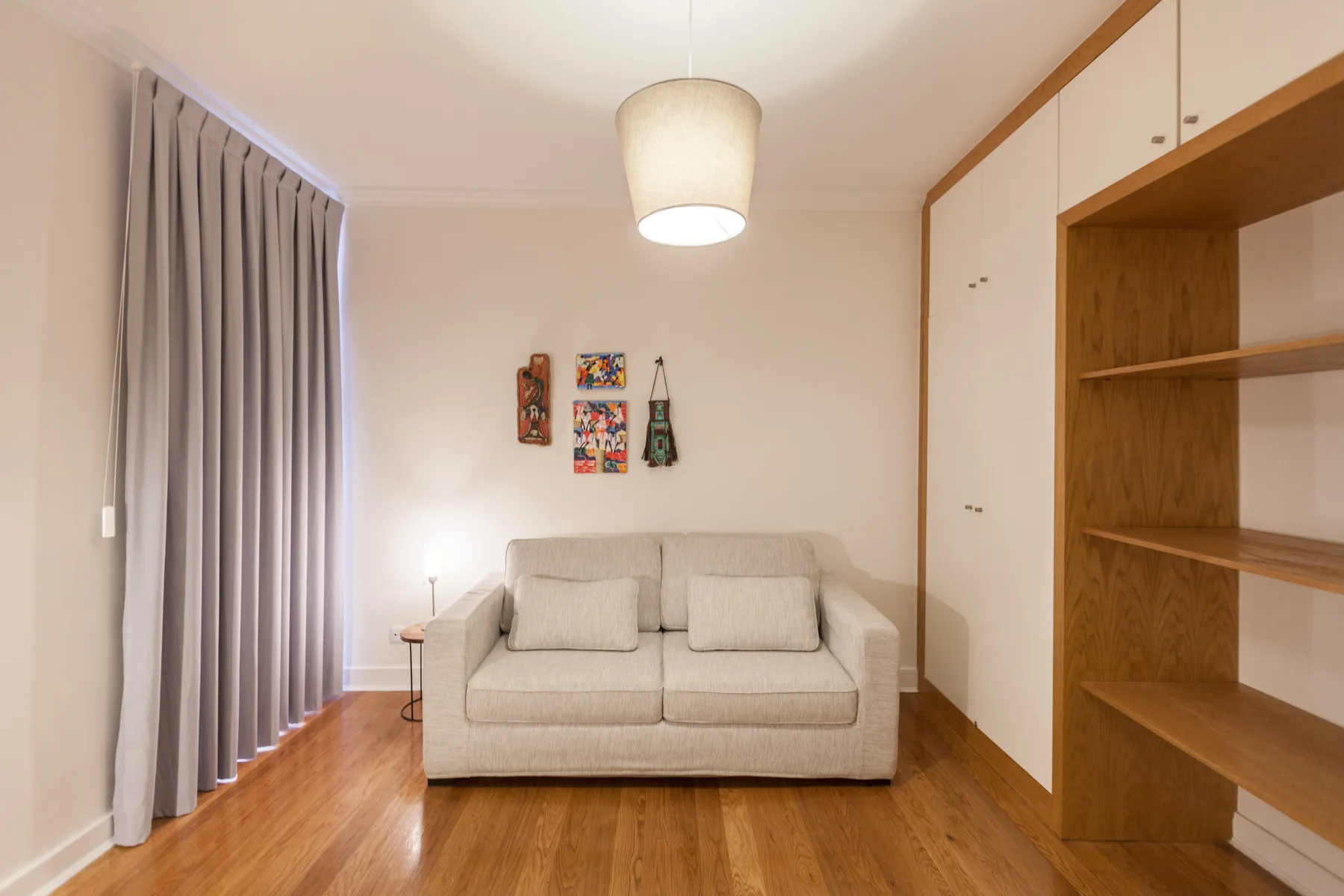 A living room with a sofa, wall art, and built-in shelving.
