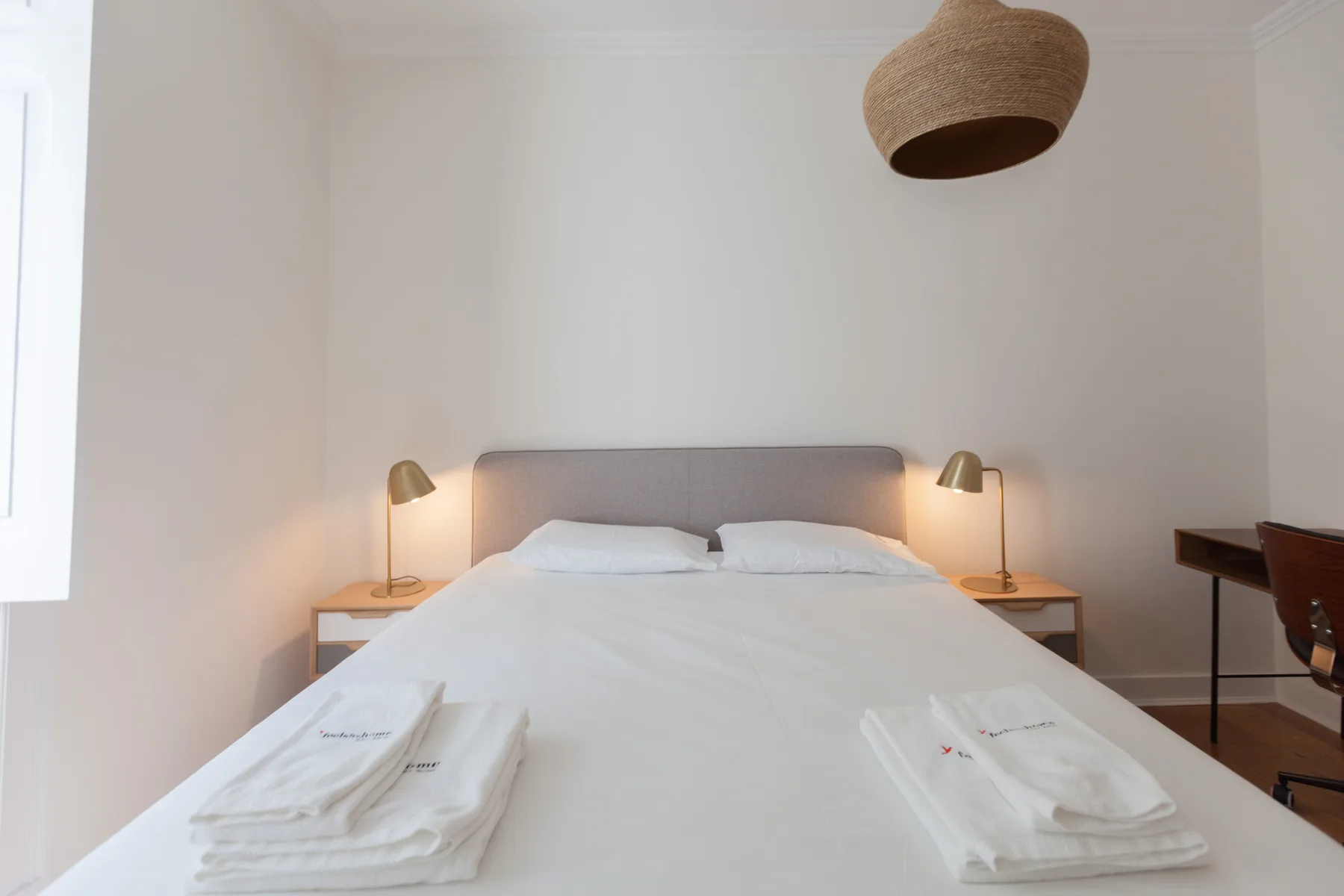A bedroom with a neatly made bed, bedside tables, and matching lamps.