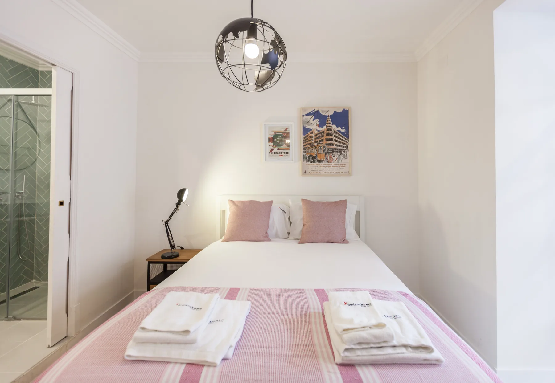 A bedroom with a neatly made bed and framed artwork above the headboard.