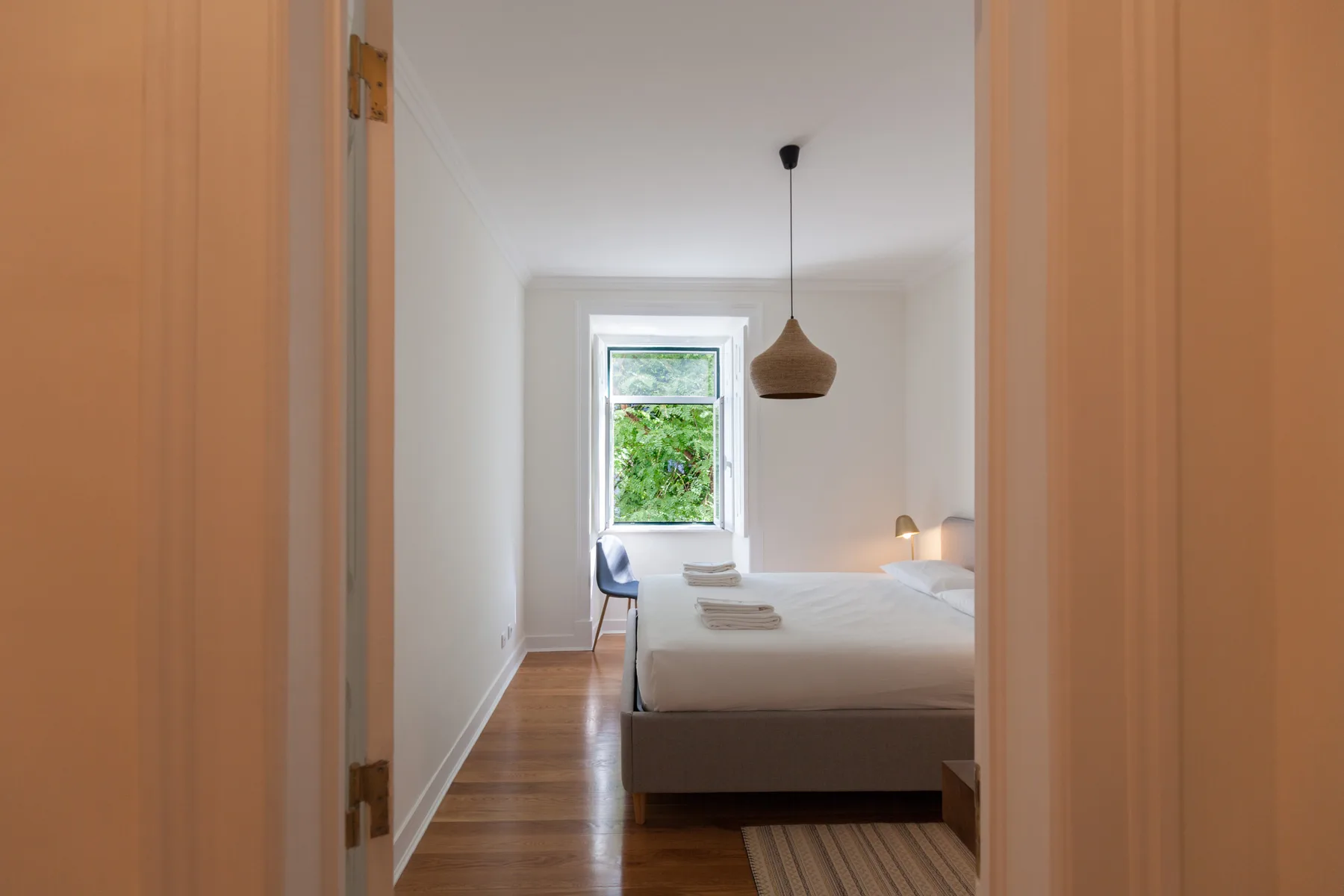 A bedroom with a bed, a window, and a pendant light.