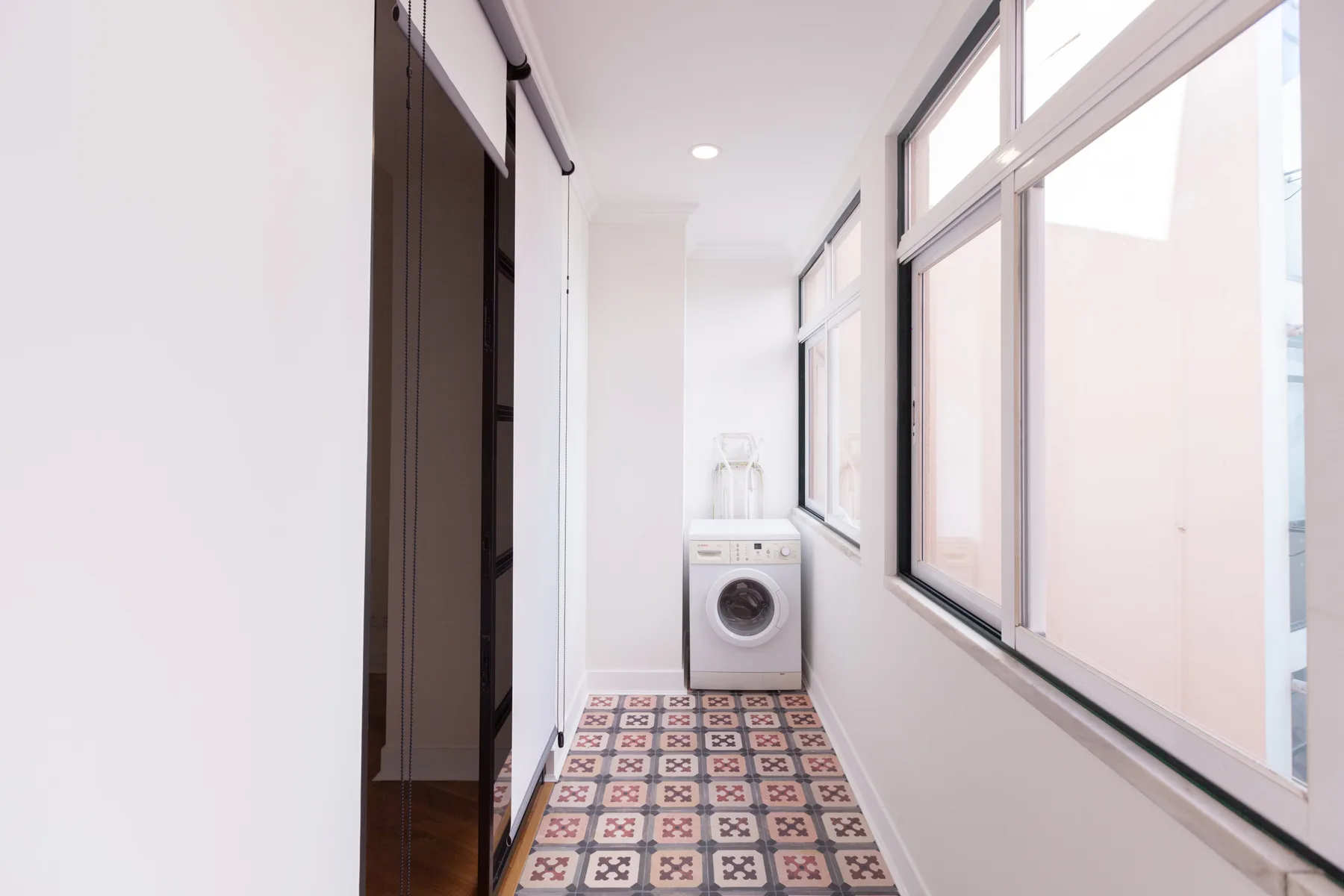 A bright laundry area with a washing machine and patterned floor tiles.