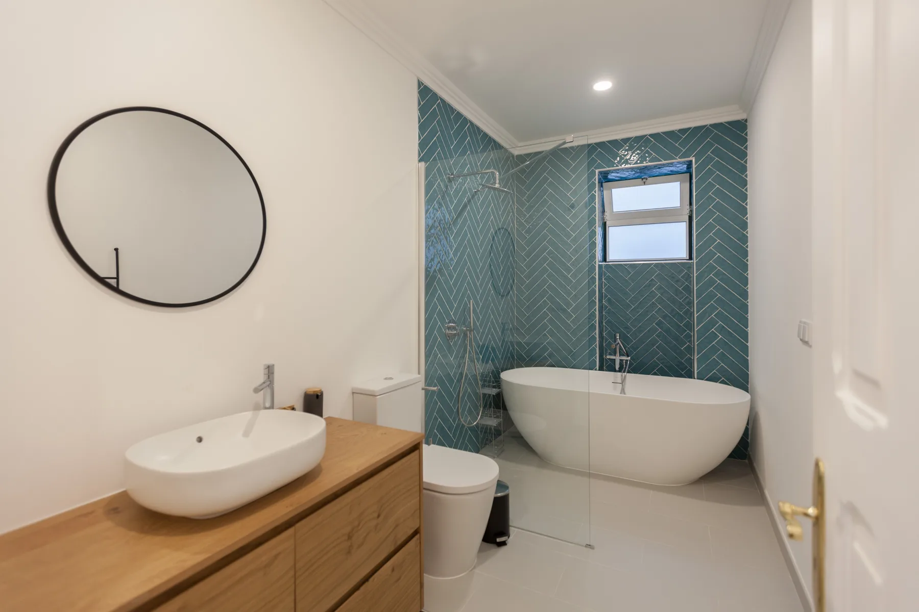 A bathroom with a freestanding tub, glass shower, and wood vanity.