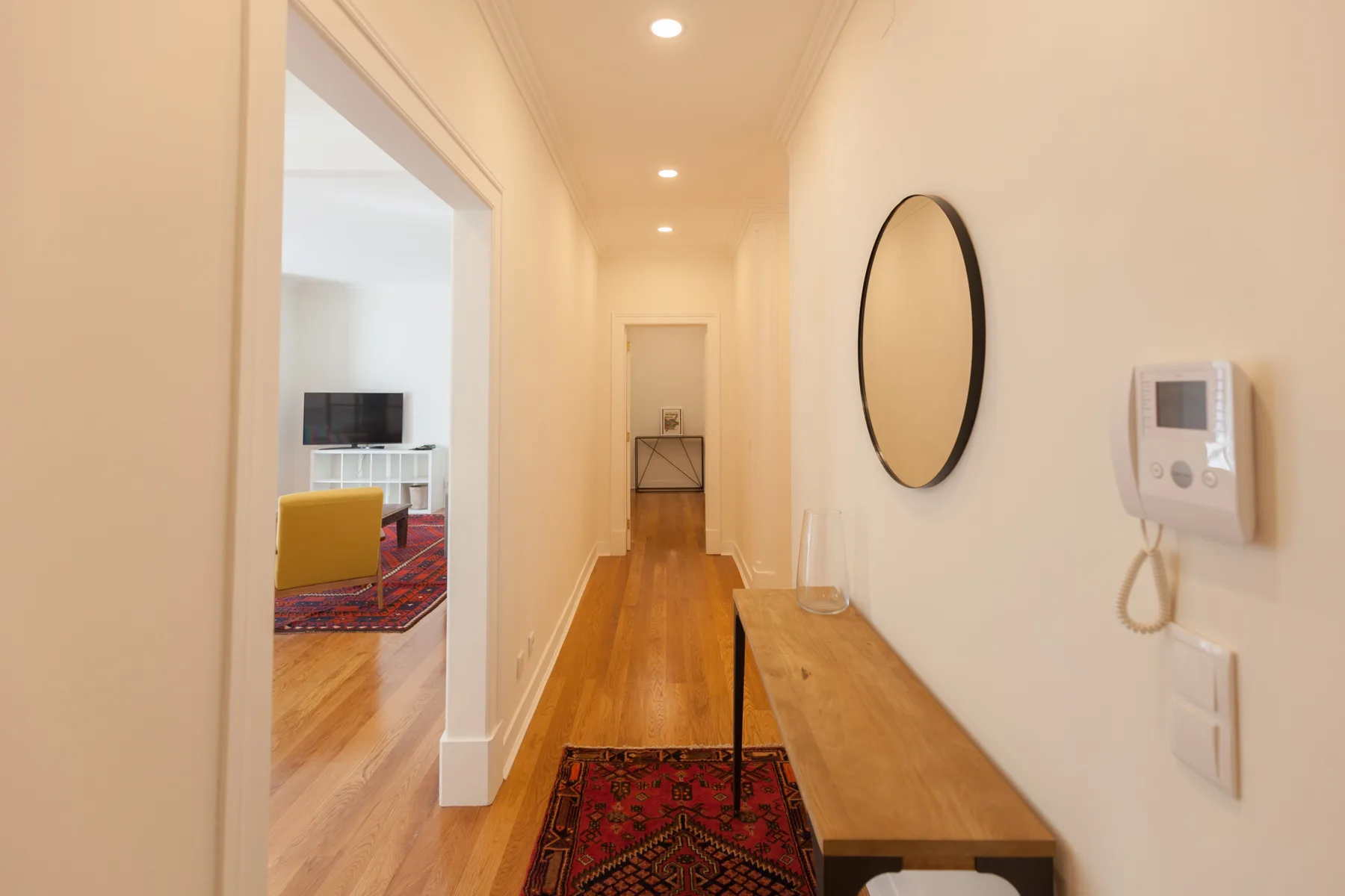 A bright hallway with wood flooring and a patterned runner.