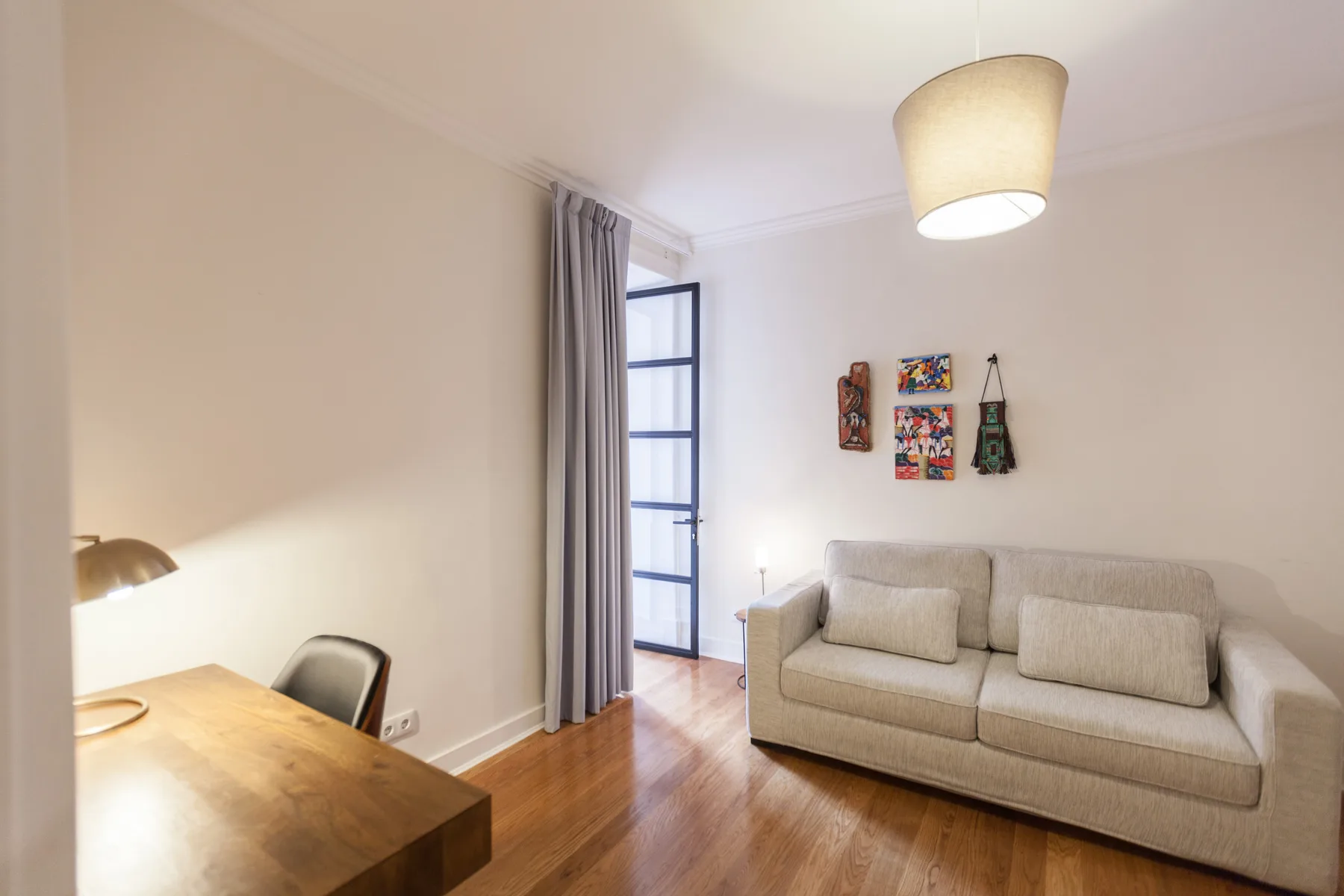 A living room with a sofa, a wooden table, and a tall window.