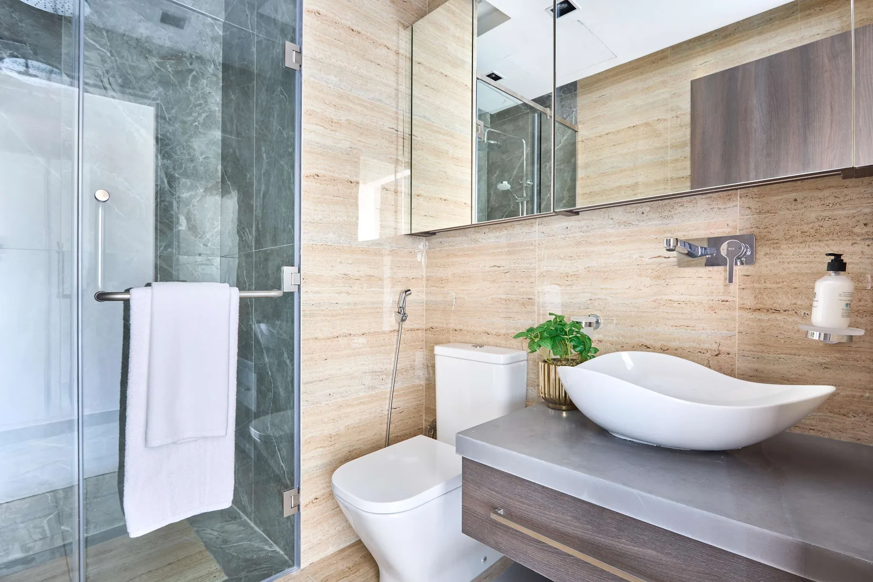 Un baño moderno con ducha de vidrio, inodoro y lavabo sobre encimera.