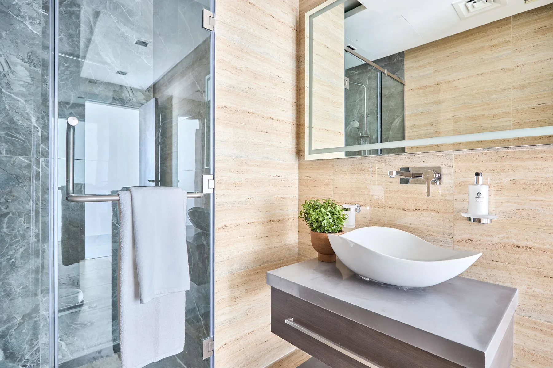 Un baño con lavabo sobre encimera, espejo de pared y ducha de vidrio.