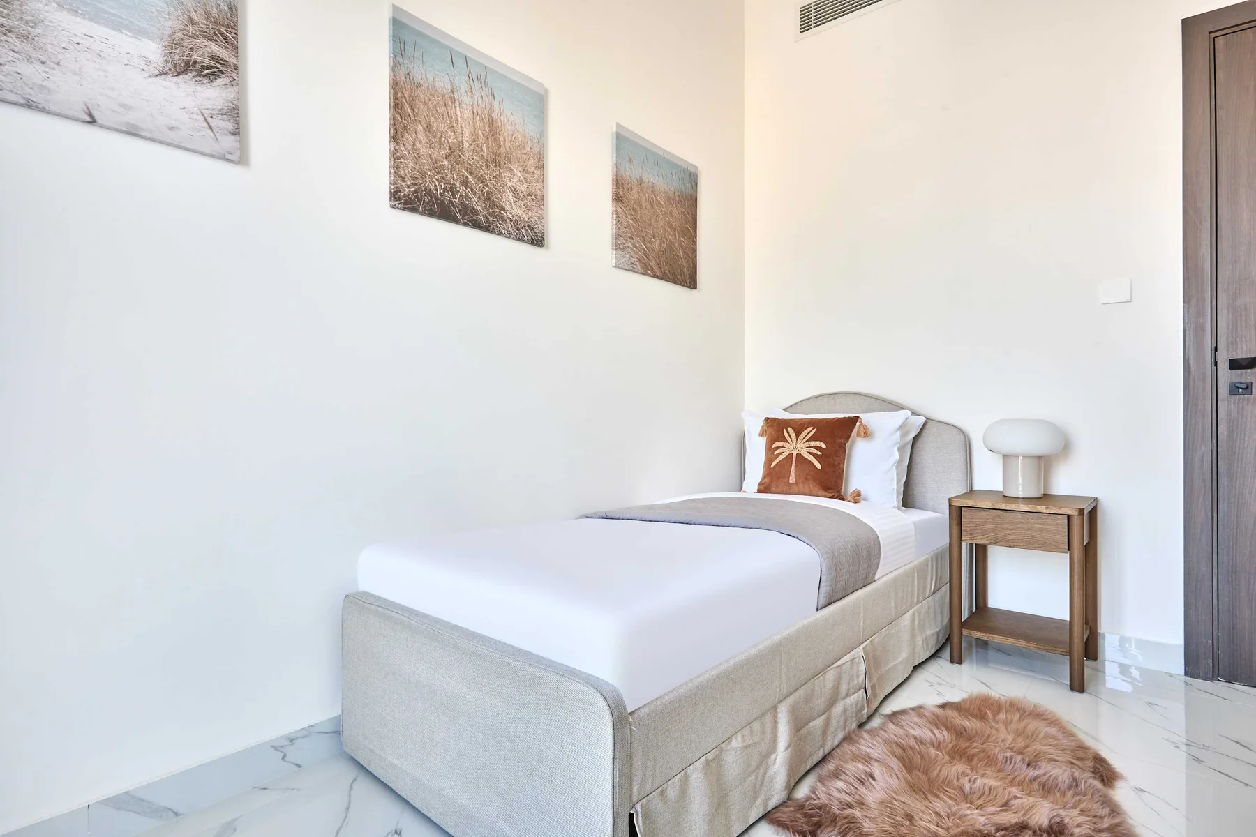 Un dormitorio con una cama tendida y cuadros de paisajes en la pared.