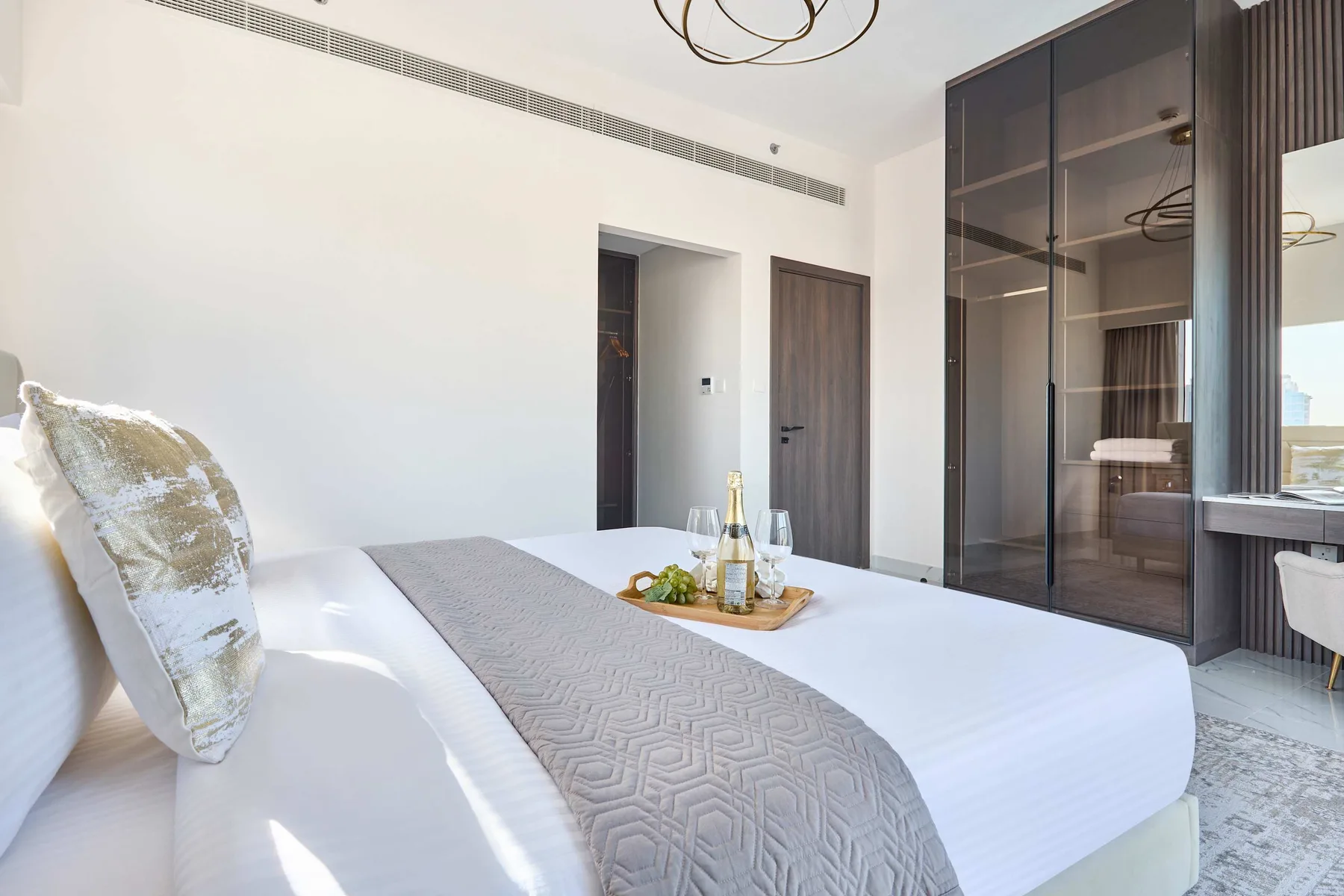 Un dormitorio luminoso con una cama bien tendida y un armario con espejos de suelo a techo.