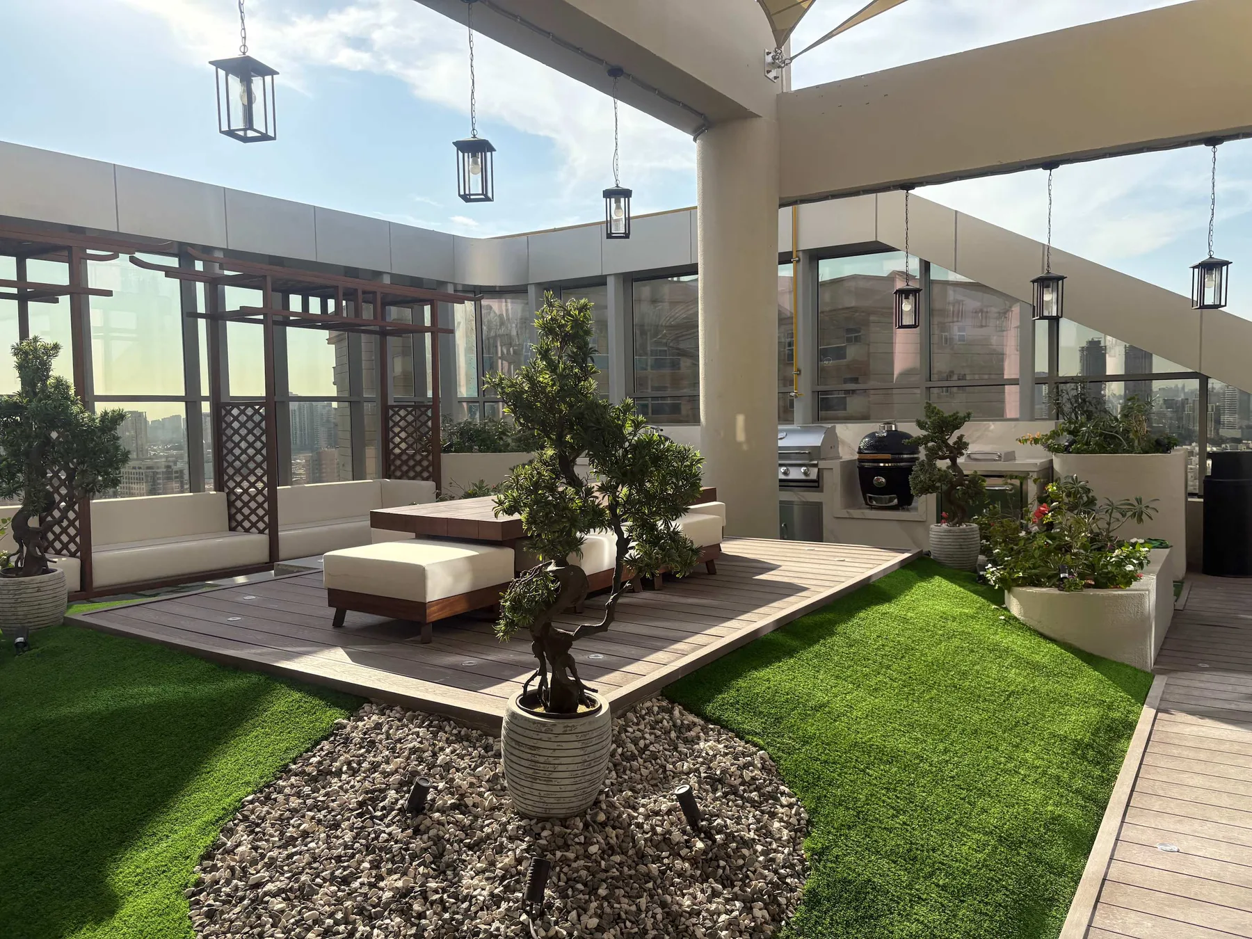 Una terraza soleada con asientos, jardineras y césped verde.