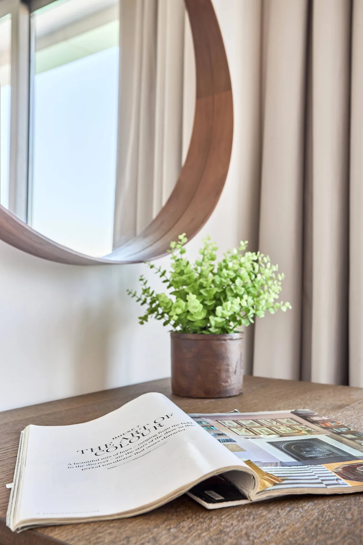 Un rincón de lectura con una revista abierta sobre una mesa junto a una planta frondosa.