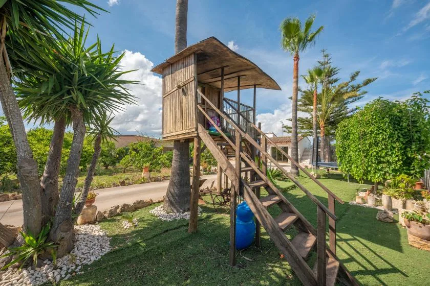 Una casita de madera se encuentra entre árboles en un jardín ajardinado.