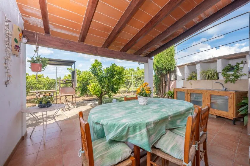 Comedor exterior cubierto con una mesa y vistas al jardín.