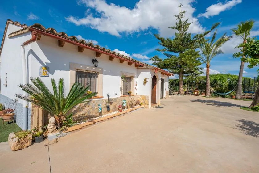 Un edificio blanco de estuco da a un patio soleado pavimentado con árboles.