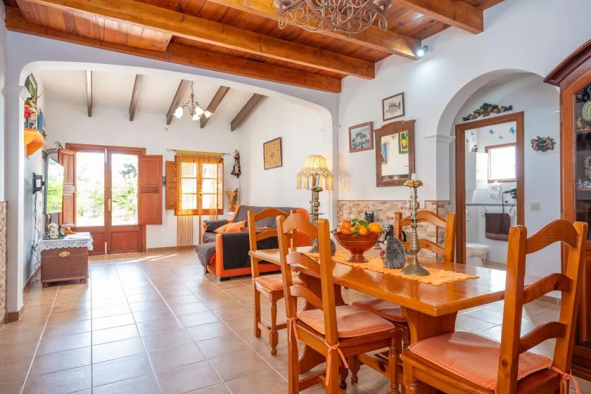 Comedor con una mesa de madera y asientos bajo vigas expuestas.