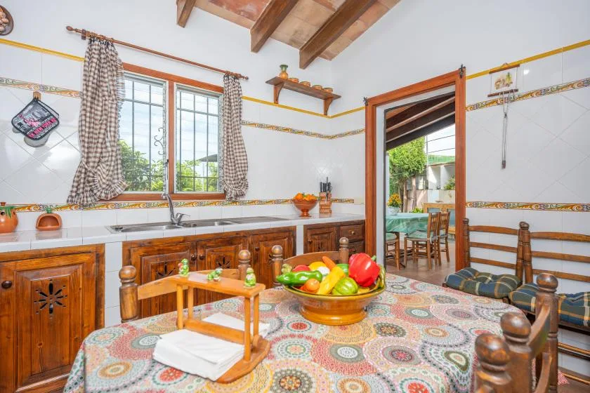 Una cocina con azulejos, gabinetes de madera, una ventana y una mesa con fruta.