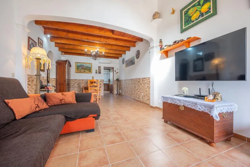 Una sala de estar con asientos, un televisor y vigas de madera expuestas en el techo.