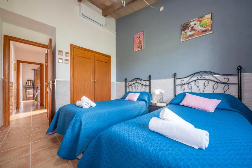 Dormitorio con dos camas cubiertas de azul y toallas blancas dobladas.