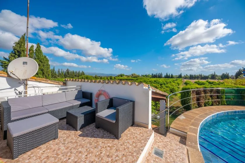 A rooftop terrace with outdoor seating and a swimming pool overlooking greenery.