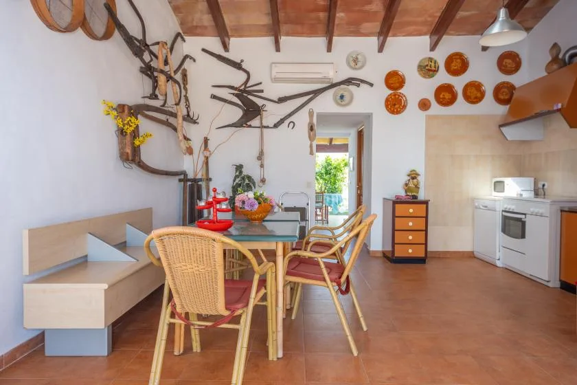 Comedor con asientos de mimbre, una mesa y la cocina al fondo.